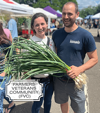Woman and Man at market holding fresh scallions. Text reads farmers veterans community (FVC)