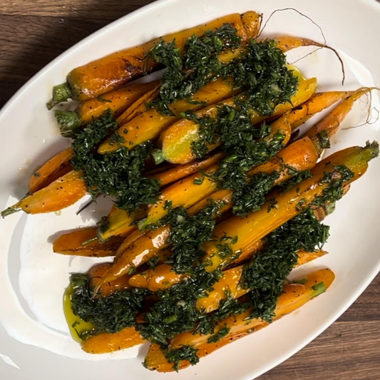 roasted carrots with pesto topping on white plate