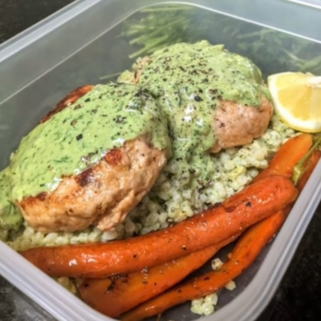 salmon patties on rice with booked carrots drizzled in carrot top pesto in a plastic container