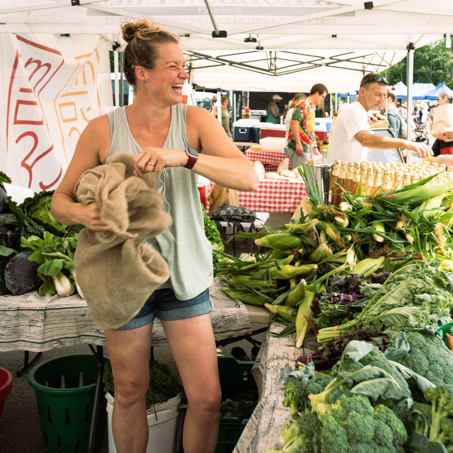 women at farmers market with vegetables in a vendor tent