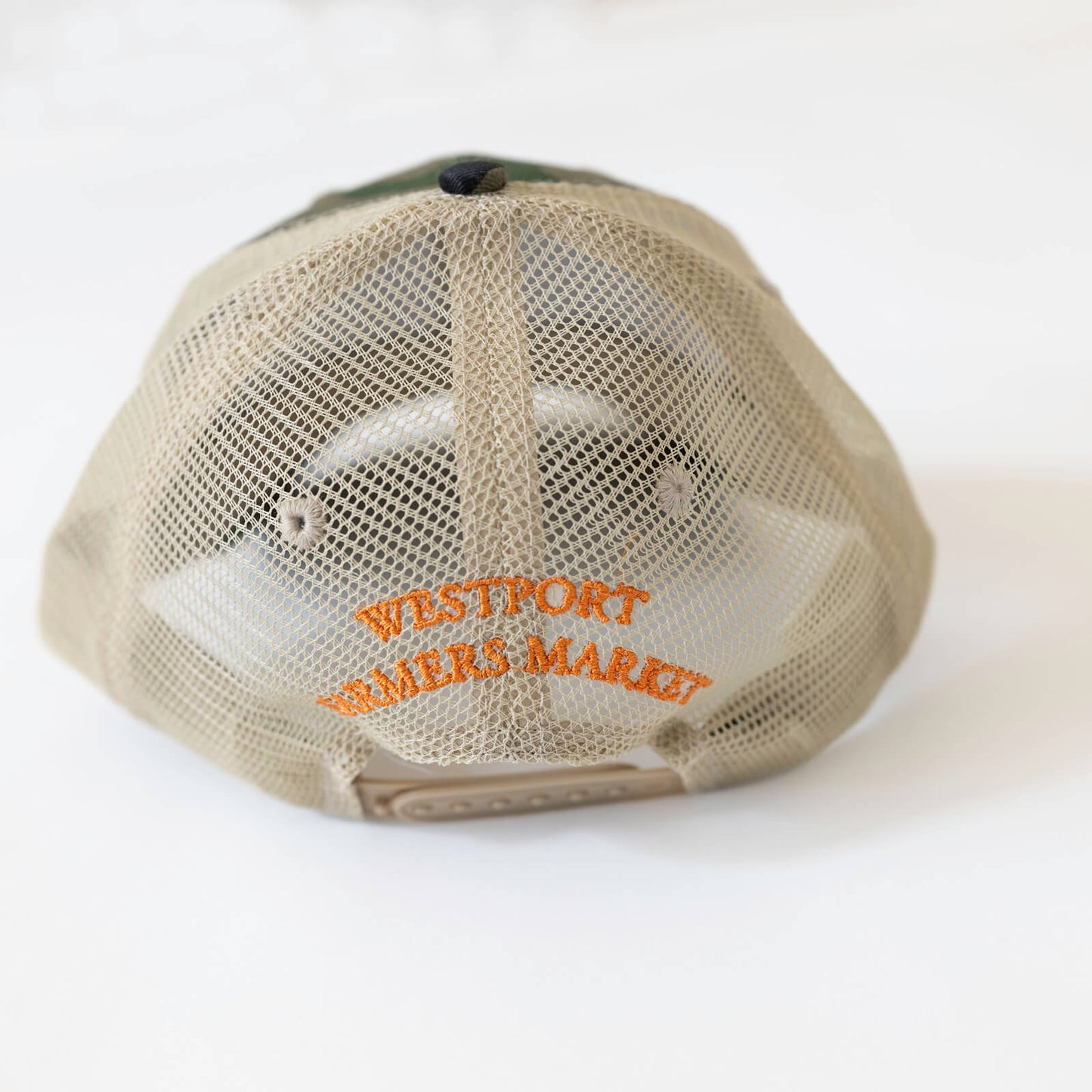 Camo baseball hate with orange text on tan back that says westport farmers market